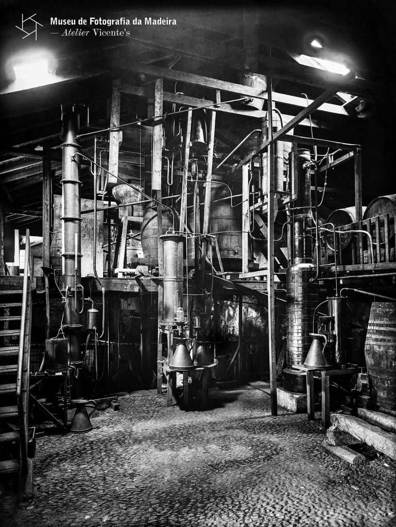 Interior da fábrica de aguardente de cana-de-açúcar (engenho) na ponte do Deão, freguesia de Santa Luzia (atual freguesia do Imaculado Coração de Maria), concelho do Funchal - Anterior a 1905